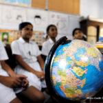 Children sit in a classroom in Chennai in front of a world globe, learning about children on the other side of the world through a schools partnership scheme, India.