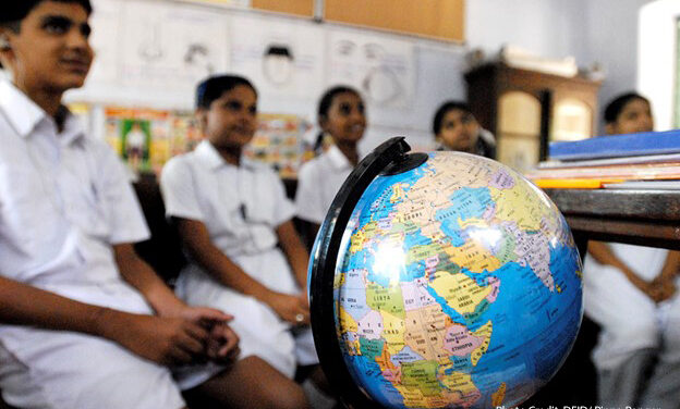 Children sit in a classroom in Chennai in front of a world globe, learning about children on the other side of the world through a schools partnership scheme, India.