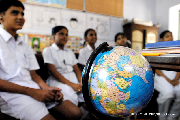 Children sit in a classroom in Chennai in front of a world globe, learning about children on the other side of the world through a schools partnership scheme, India.