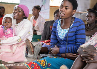 Girls sitting on the floor, including a girl with her baby, at a community-based learning centre in Dedza District.