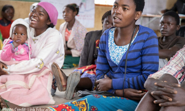 Girls sitting on the floor, including a girl with her baby, at a community-based learning centre in Dedza District.