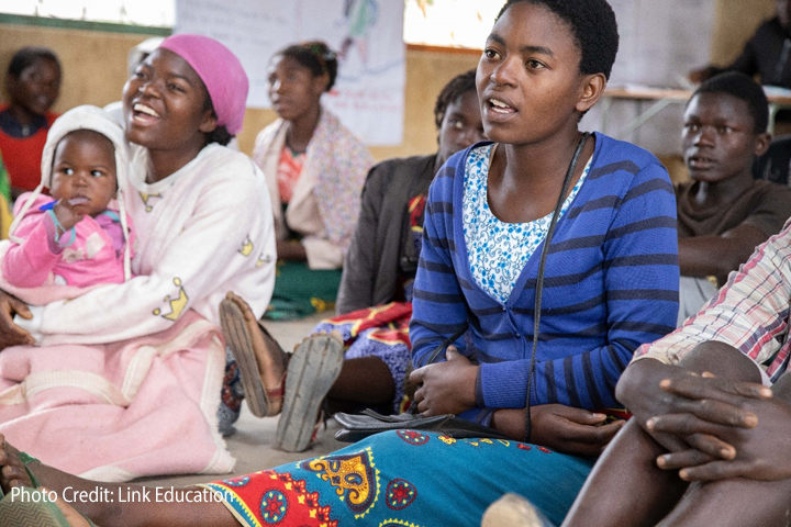 Girls sitting on the floor, including a girl with her baby, at a community-based learning centre in Dedza District.