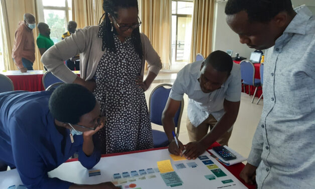 Four educators work around a chart, adding in design elements as the development team design the blended CPD delivery approach in Rwanda.