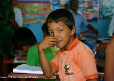 Boy sits at his desk in the classroom looking at the camera, Amazon jungle, Peru