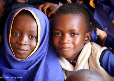 A young girl and boy smile at the camera in a classroom in Sierra Leone