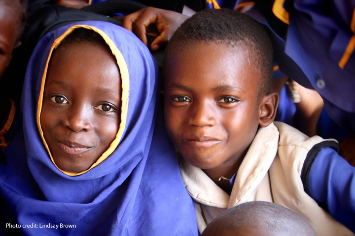 A young girl and boy smile at the camera in a classroom in Sierra Leone