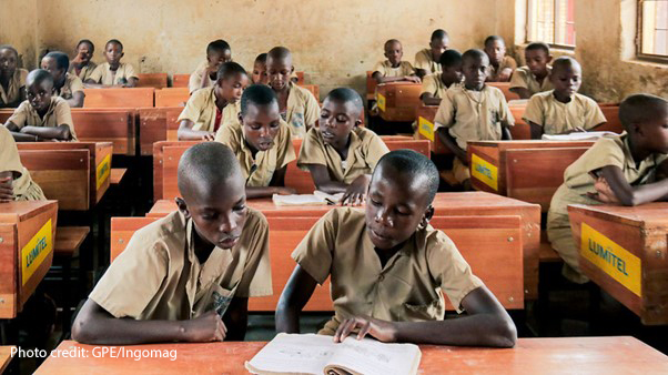 Alt text: Boys share books in class in Burundi