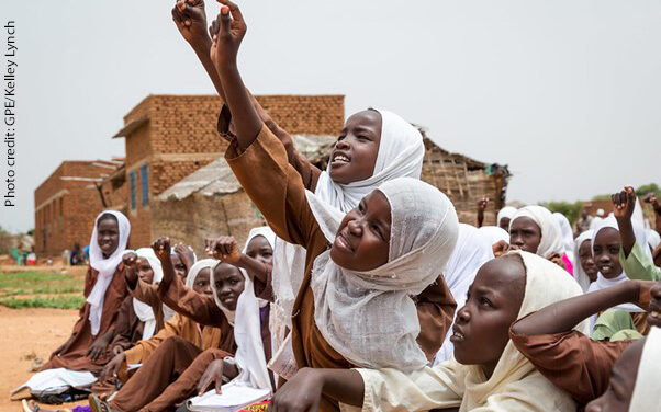 students try to get the teacher’s attention to answer a question, Sudan