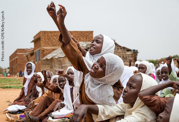 students try to get the teacher’s attention to answer a question, Sudan