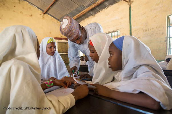 Four girls in class with their teacher Tukur Yusuf at Miga Central Primary School, (a secular ‘Western’ school), Jigawa State, Nigeria
