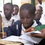 Abdullahi, who has a visual impairment, receiving support from his teacher at school in Nigeria.