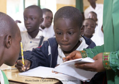 Abdullahi, who has a visual impairment, receiving support from his teacher at school in Nigeria.