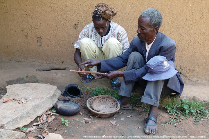 A senior rainmaker in the Nganyi community, Obedi Osore Nganyi (right), instructs Reuben Asitwa Okonda, an apprentice, on how to do the pot blowing. During the rainmaking activities, the rainmakers sometimes stay for hours or even days in the shrines and at this point it is normally the work of the assistant to keep them supplied with food and water.