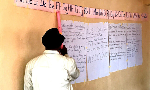 Teacher points to letters in a make-shift classroom, Sierra Leone.