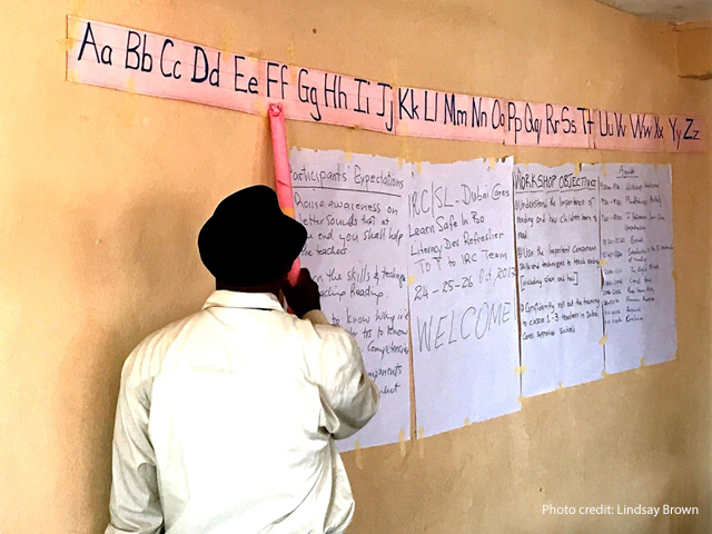 Teacher points to letters in a make-shift classroom, Sierra Leone.