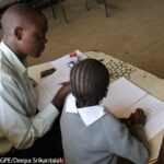 A male enumerator gives the Early Grade Mathematics Assessment to a girl in the Marikani Government School, Nairobi, Kenya.