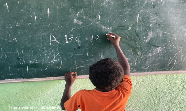 Young boy learns to write the letters of the alphabet with chalk on the blackboard of his primary school classroom, Somali Region, Ethiopia.