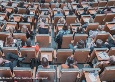 The back of tops of heads of students sitting in a university lecture theatre.