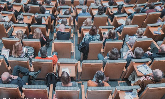 The back of tops of heads of students sitting in a university lecture theatre.