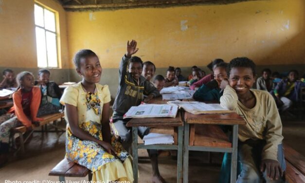 Children laugh and smile to the front of the classroom during a lesson.