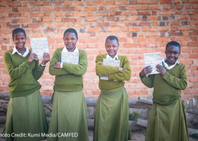 Students Hadija, Anna, Maria, and Jesca holding their My Better World self-development books outside their school in Tanzania’s Kilolo district.