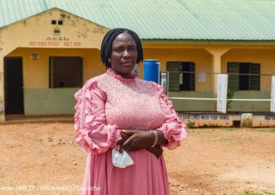 Nigerian women teacher stands in the playground outside her classroom.