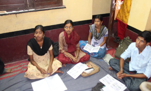 Students sit cross-legged on the floor in a class discussion, Bankura West Bengal, India.