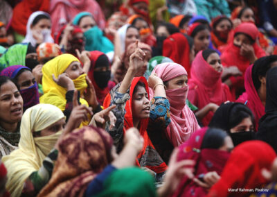 Indian women protesting. Wearing brightly coloured clothes, some with hand raised.