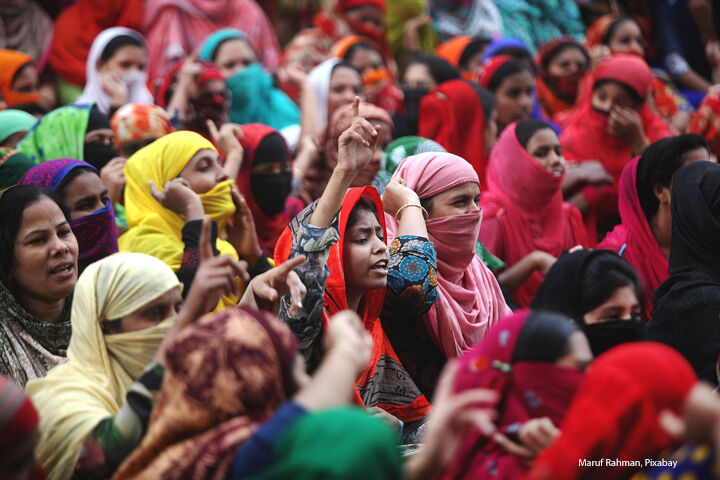 Indian women protesting. Wearing brightly coloured clothes, some with hand raised.