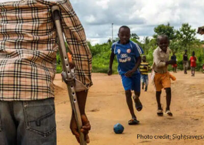 View from behind a child on crutches, watching his friends play at a Sightsavers supported inclusive school in Cameroon.