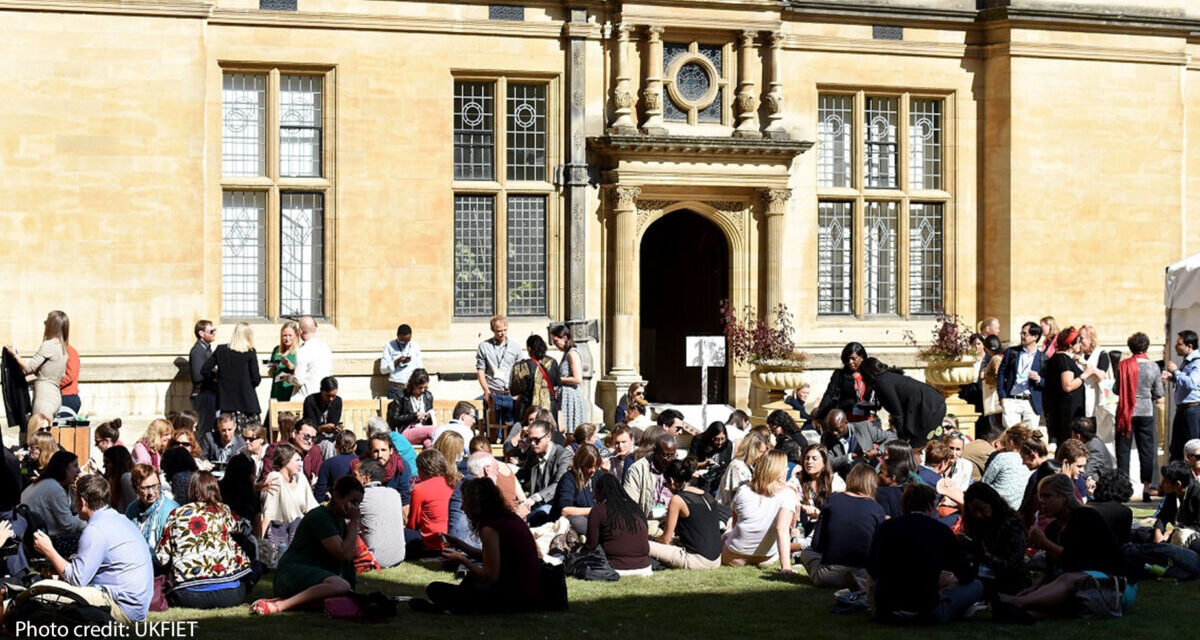 UKFIET conference participants sit outside on the grass during a lunchbreak.