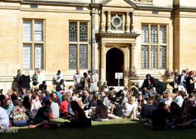 UKFIET conference participants sit outside on the grass during a lunchbreak.