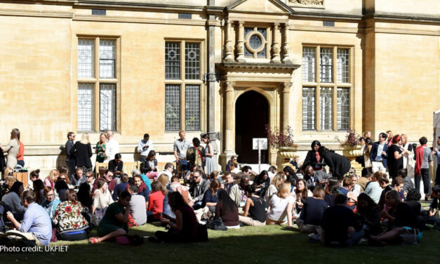 UKFIET conference participants sit outside on the grass during a lunchbreak.