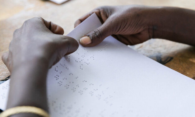 Hands reading a braille page. A blind student at Sebeta School for the Blind checks her answers after taking a geography exam; Sebeta, Oromia, Ethiopia.