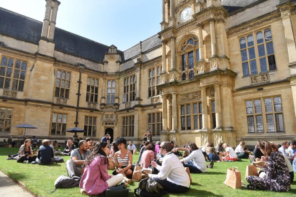 Lunchtime delegates sitting on the grass at UKFIET 2023 in Oxford