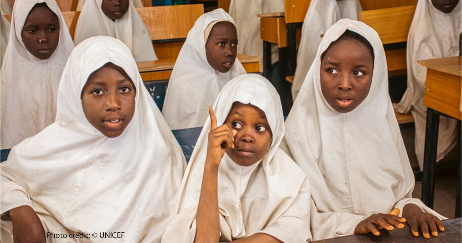 Children gather for Girls-for-Girls (G4G) peer mentoring sessions in Katsina state, Nigeria. School girls in white head scarves sitting at desk one with her finger up to ask a question