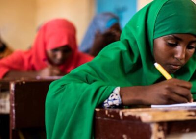 Alt text: Girls sit working at their desks in a classroom in Somalia. Girl in foreground wearing a green hijab