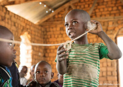 "Hello?" A student talks on a "telephone" (cut-up plastic bottle on a string) in a pre-primary class held in a small rural church. The volunteer teacher works with the students using innovative teaching and learning materials made of locally found objects. Mpanda District, Katavi Region, Tanzania