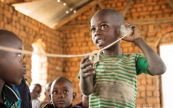 "Hello?" A student talks on a "telephone" (cut-up plastic bottle on a string) in a pre-primary class held in a small rural church. The volunteer teacher works with the students using innovative teaching and learning materials made of locally found objects. Mpanda District, Katavi Region, Tanzania