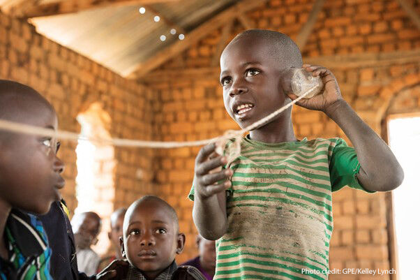 "Hello?" A student talks on a "telephone" (cut-up plastic bottle on a string) in a pre-primary class held in a small rural church. The volunteer teacher works with the students using innovative teaching and learning materials made of locally found objects. Mpanda District, Katavi Region, Tanzania