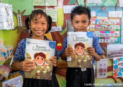 A young girl and boy hold up their textbooks in their classroom, Indonesia.