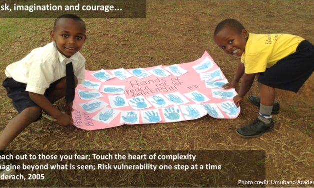 Two schoolchildren hold out their poster with ‘hand of peace’ prints from all the class. Text in the middle of hand prints - Hands of Peace not for fighting!!! Text overlaying image: Risk, imagination and courage..... Reach out to those you fear; Touch the heart of complexity. Imagine beyond what is seen; Risk vulnerability one step at a time Ledrach, 2005