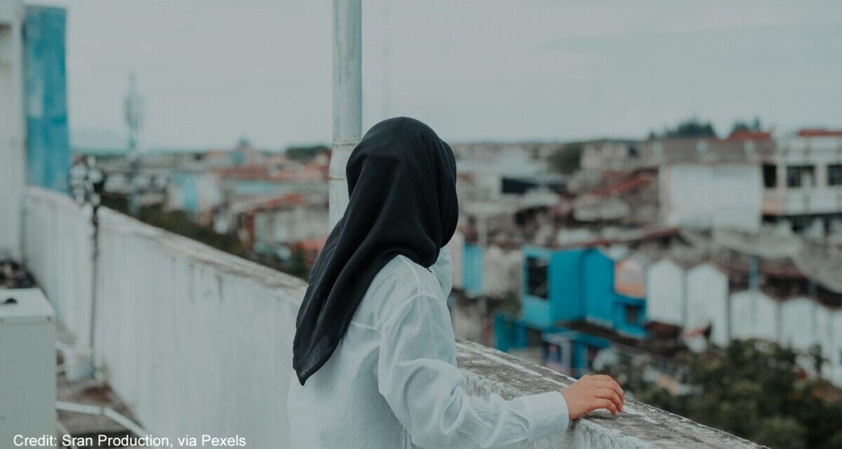 Woman looking at a cityscape from a rooftop.