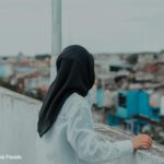 Woman looking at a cityscape from a rooftop.