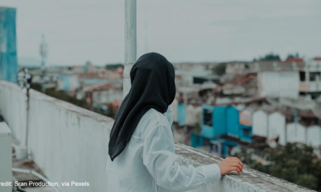 Woman looking at a cityscape from a rooftop.