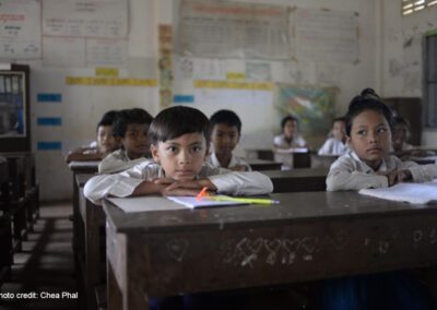 Young boys and girls sit looking out over their desks in class, Cambodia.