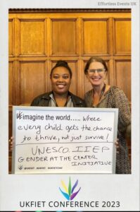 Selfie taken at the UKFIET Conference 2023 of Sally and Fabricia  holding a board with " We Imagine the world where every child gets the chance to  thrive, not just survive!  UNECO IIEP Gender at the Centre Initiative