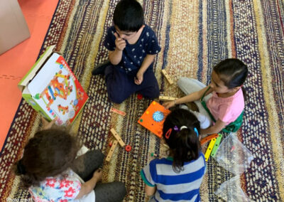 A group of young children sit together playing on a rug, Moldova.