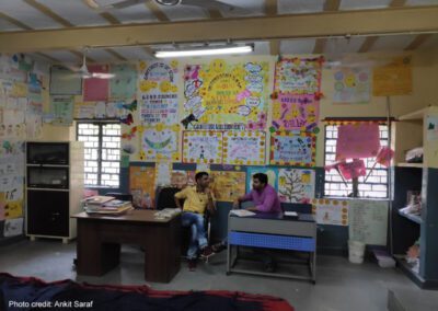 Two male teachers sit in a classroom and compare notes, India.