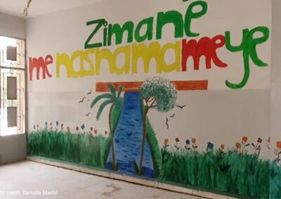 Mural on a wall in a Corridor in the school run by AANES in Qamishli. "Zimane me Nasnama me ye" with a meadow and a stream with trees.